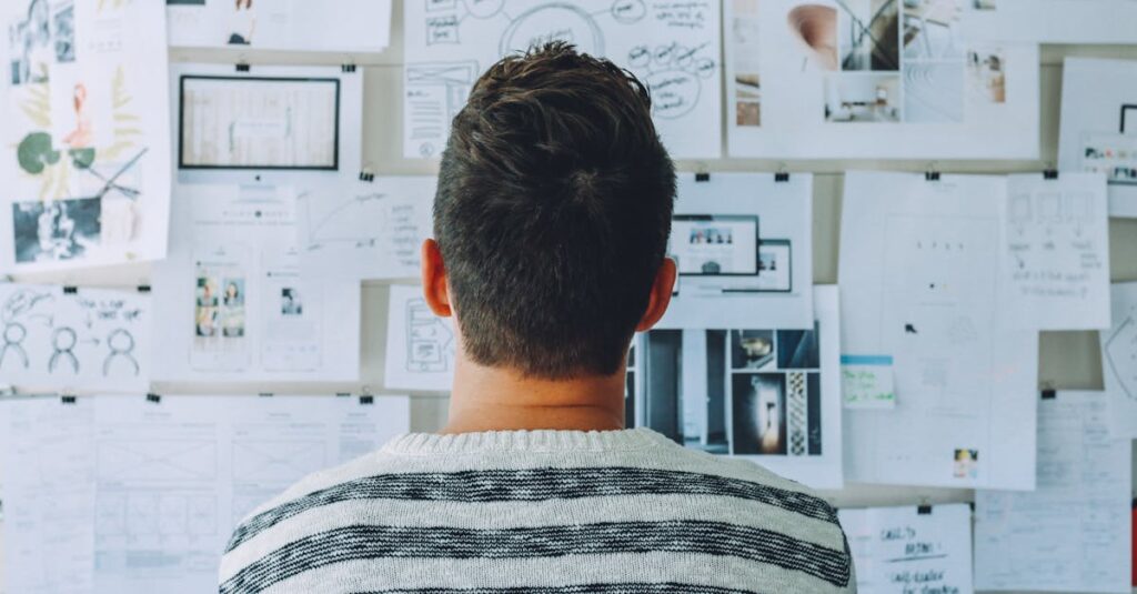 A man stands in front of a wall filled with creative ideas and plans. Ideal for innovation themes.